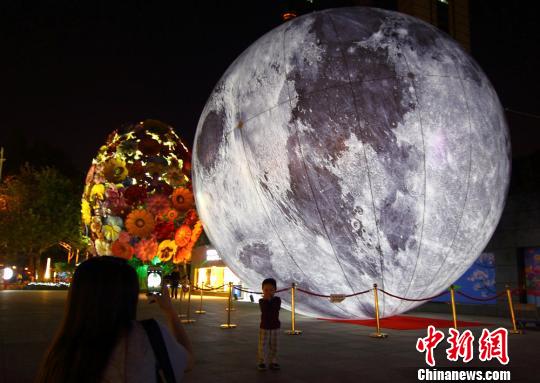 母亲为儿子在“月亮”前拍照留念。 李珂 摄