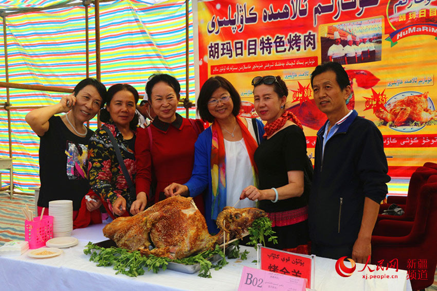 美味的烤全羊吸引内地游客合影留念。冉波 摄